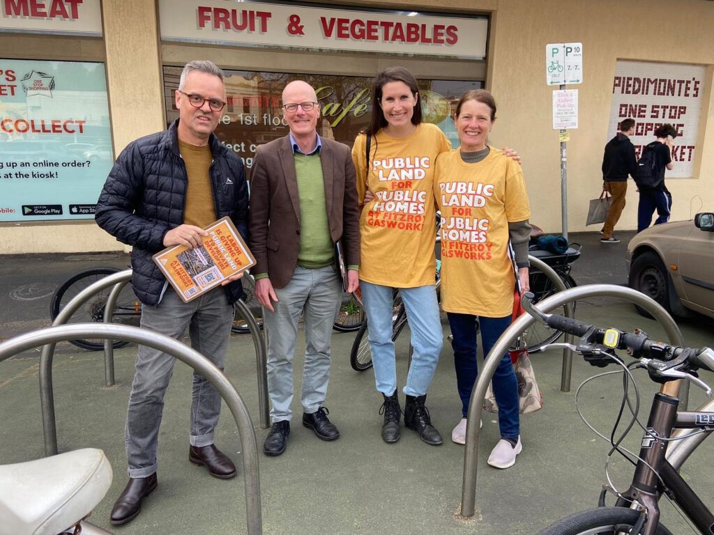 Four people, including Tim Read and Cr. Sophie Wade, smiling for a photo. They are wearing and holding merch that reads "Public land for public homes at Fitzroy Gasworks"