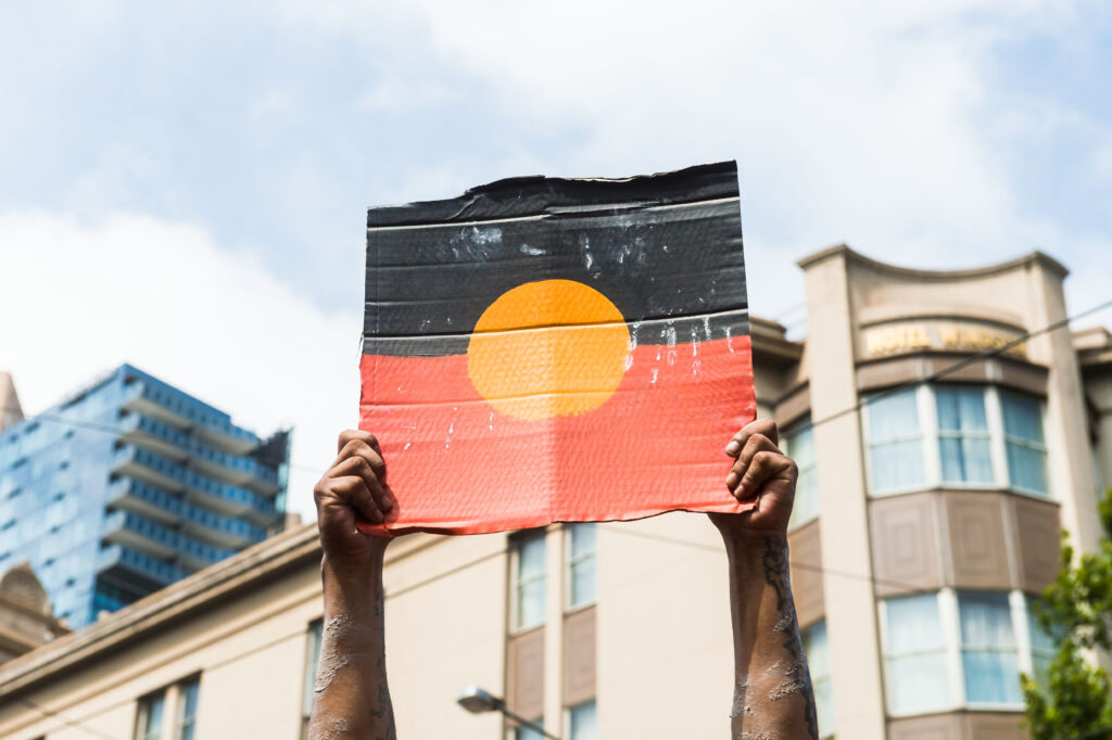 Hands holding a sign with the Aboriginal flag